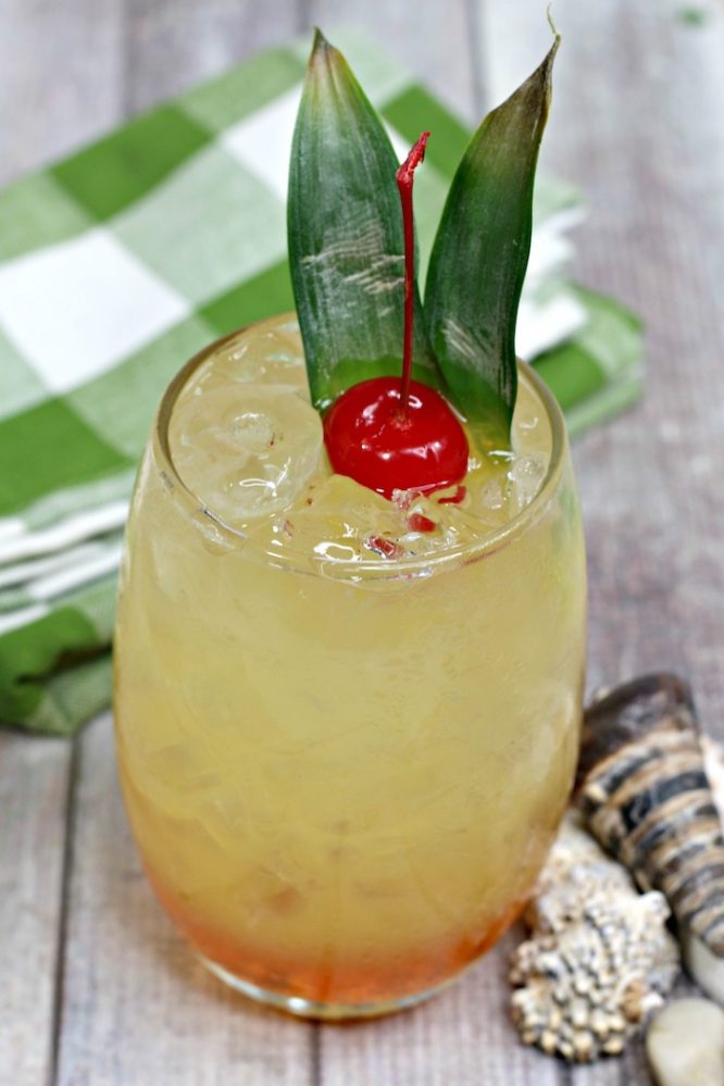 Orange and Pineapple Polynesian cocktail on a green check napkin with cherry garnish